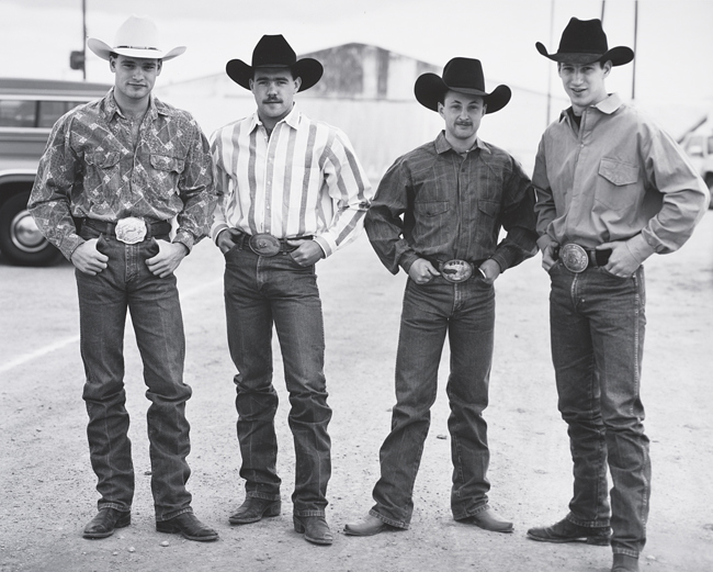 [four young men in cowboy clothes, all with hands in pockets]