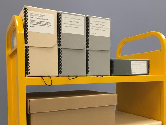 Image of a yellow book truck with archive boxes on its shelves.
